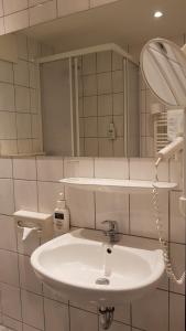 ein Badezimmer mit einem weißen Waschbecken und einem Spiegel in der Unterkunft Hotel & Restaurant Fricke in Hämelerwald