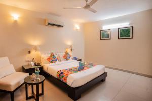 een slaapkamer met een bed, een bank en een stoel bij FabHotel Anutham Saket in New Delhi