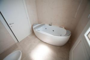 a white bathroom with a tub and a toilet at Antica Masseria Ficazzana - Tenuta in Marina di Pescoluse