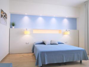 a bedroom with a bed with a blue blanket at Hotel Perla Gaia in San Vito lo Capo