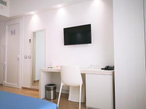 a white room with a desk and a television on the wall at Hotel Perla Gaia in San Vito lo Capo