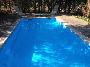 a blue swimming pool with two chairs in a yard at El Refugio. in Teruel
