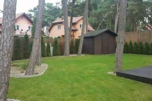 a group of trees in a yard with a house at Hire House in Pobierowo