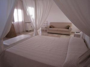 a bedroom with a white bed and a couch at Antica Masseria Ficazzana - Tenuta in Marina di Pescoluse