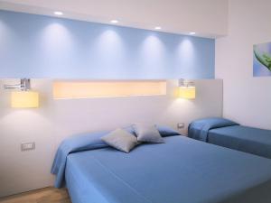 a bedroom with a blue bed and two lights at Hotel Perla Gaia in San Vito lo Capo