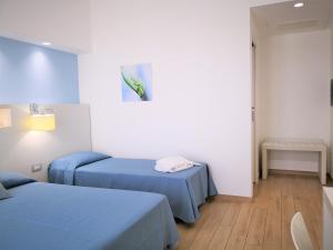 a hospital room with two beds and a fish on the wall at Hotel Perla Gaia in San Vito lo Capo