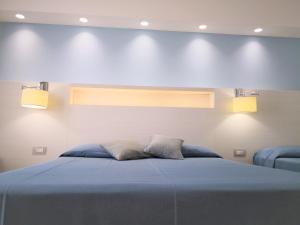 a bedroom with a blue bed with two pillows at Hotel Perla Gaia in San Vito lo Capo