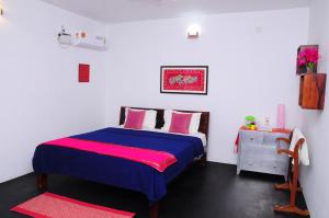 a bedroom with a blue bed and pink pillows at Villa Anna Pondy in Puducherry