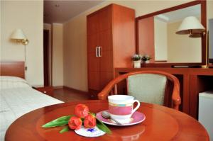 una mesa de madera con una taza de café y flores. en Hotel Turist, en Yuzhno-Sakhalinsk