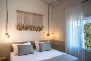 1 dormitorio con cama con almohadas y ventana en Avali luxury houses en Gaios