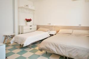 una camera ospedaliera con due letti e un comò di Hotel Happy a Marina di Pietrasanta