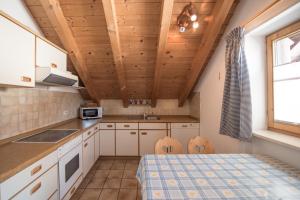 Il comprend une cuisine avec des plafonds en bois, une table et des chaises. dans l'établissement Ferienwohnung Fauser, à Oberstdorf