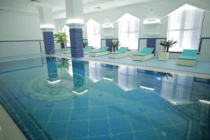 ein Pool in einem Hotel mit blauen Stühlen und Wasser in der Unterkunft Sultan Palace Hotel in Atyrau