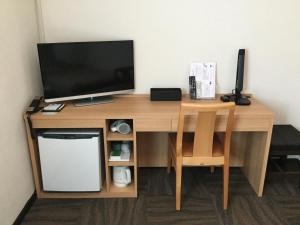 a wooden desk with a television and a chair at Maebashi Business Hotel Luka in Maebashi