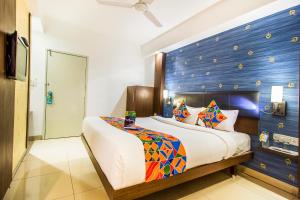 1 dormitorio con 1 cama grande y pared azul en FabExpress Kalyan, en Vadodara