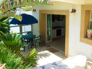 a patio with a table and a blue umbrella at The Golden Rainbow - SEAFRONT apartments in Villaggio San Leonardo