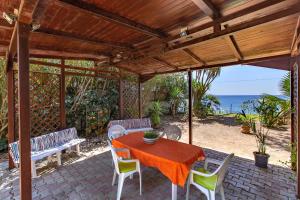 eine Terrasse mit einem Tisch, Stühlen und Meerblick in der Unterkunft Ecocasette in Syrakus