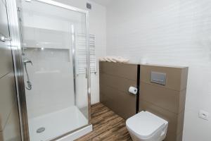 a white bathroom with a shower and a toilet at Rosa Apartamenty in Dąbki +79 photos