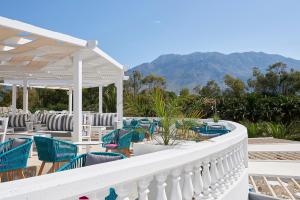 um pátio com cadeiras e mesas e montanhas ao fundo em Mythos Palace Resort & Spa em Georgioupolis