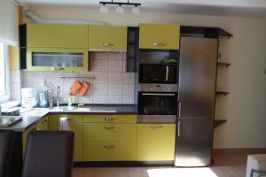 a kitchen with yellow cabinets and a stainless steel refrigerator at Árnyas apartman in Pécs