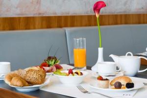 einen Tisch mit Frühstückszutaten und eine Vase mit einer Blume in der Unterkunft Mercure Hotel Frankfurt Eschborn Helfmann-Park in Eschborn