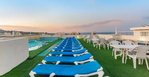 una fila di tavoli e sedie su un tetto con piscina di Cerviola Hotel a Marsaskala