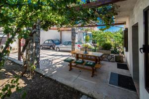 a patio with a wooden table and a bench at apartman Babić in Krk