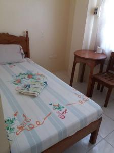 a bed with a blue and white blanket and a table at Eco Pension in Surigao