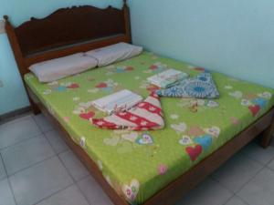 a bed with a green blanket with hearts and flowers at Eco Pension in Surigao