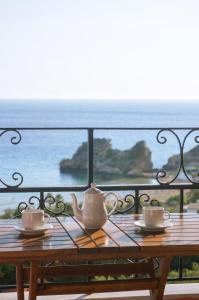 una mesa con tazas y platillos en el balcón en Fotini's Apartments - Pelekas Beach, en Pelekas