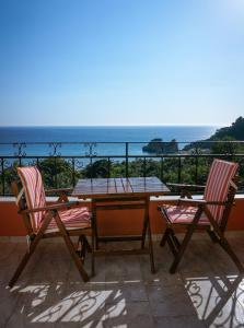 派萊卡斯的住宿－Fotini's Apartments - Pelekas Beach，阳台配有一张桌子和两把椅子,享有海景