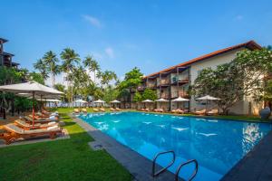 a pool at the resort with lounge chairs and umbrellas at Mermaid Hotel & Club in Kalutara