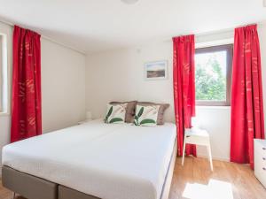 1 dormitorio con 1 cama con cortinas rojas y ventana en Detached bungalow in Kamperland near sea, en Kamperland