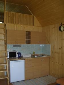 a kitchen with wooden cabinets and a white refrigerator at Chaty Dagmar in Liptovský Mikuláš