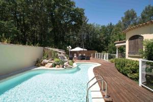 a swimming pool in a backyard with a wooden deck at Mas Des Sentes in Nans-les-Pins