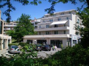 un grande edificio bianco con auto parcheggiate in un parcheggio di Residence Services Calypso Calanques Plage a Marsiglia