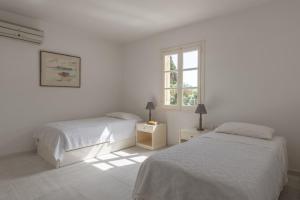 a white bedroom with two beds and a window at Traditional Town Home with Amazing View! in Mikonos