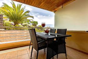 a black table and chairs on a balcony with a window at 2BED Ocean Apartment in Los Gigantes in Puerto de Santiago