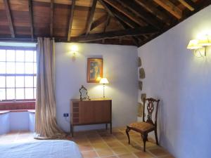 een slaapkamer met een bed en een stoel bij Haciendas del Valle - Las Kentias in Valle de Guerra