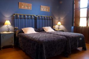 1 dormitorio con 1 cama grande y paredes azules en Hotel Rural La Veleta, en Murias de Rechivaldo