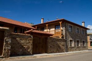 a stone house with a wooden gate and a balcony at Hotel Rural La Veleta in Murias de Rechivaldo
