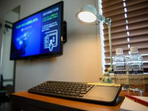 laptopa siedzącego na biurku przed telewizorem w obiekcie Ebisuholic Hotel w Tokio