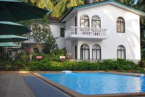 a house with a swimming pool in front of it at Albuquerque BetterHomes, Goa in Candolim