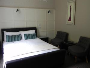 a bedroom with a bed and two chairs at Pearse Lodge in Sligo