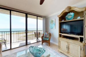 a living room with a large television and a balcony at Lighthouse Towers Condominium in Clearwater Beach