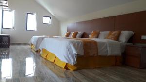 a bedroom with a large bed with white and orange sheets at TULIP HOTEL & APARTMENT in Cameron Highlands