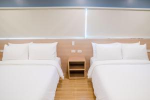 two beds in a hotel room with white pillows at Bridge Hotel in Cagayan de Oro