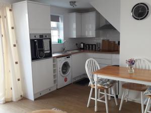 uma cozinha com uma máquina de lavar roupa e uma mesa em The Cottage em Redruth