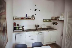 una cocina con armarios blancos y fregadero en la casa in collina en Vicoforte