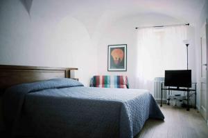 ein Schlafzimmer mit einem Bett, einem Stuhl und einem TV in der Unterkunft la casa in collina in Vicoforte